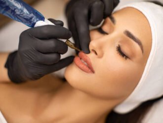 Make up artist applying permanent make up on lips at beauty treatment. Beautician contouring young woman's lips and coloring it with special tool. She do the precise shaping crayon and then microblading.