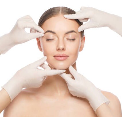 istockphoto-1249362060-612x612 Close-up portrait of young woman standing with naked shoulders and neck, face is touched by beauticians in gloves, preparing her for plastic surgery procedures, isolated on white background