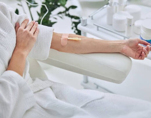 istockphoto-1312587608-612x612 Cropped head portrait of unrecognized female patient sitting in medicine armchair while receiving IV infusion in wellness center