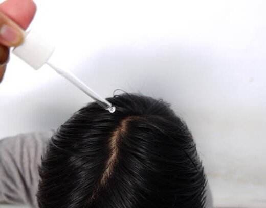 Southeast asian man dropping serum onto his hair, top view Southeast asian man dropping serum onto his hair, top view