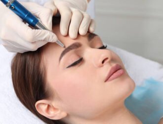 Young woman during procedure of permanent eyebrow makeup in beauty salon, closeup